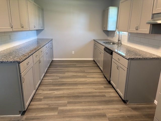 kitchen featuring dark stone countertops, sink, hardwood / wood-style flooring, and dishwasher