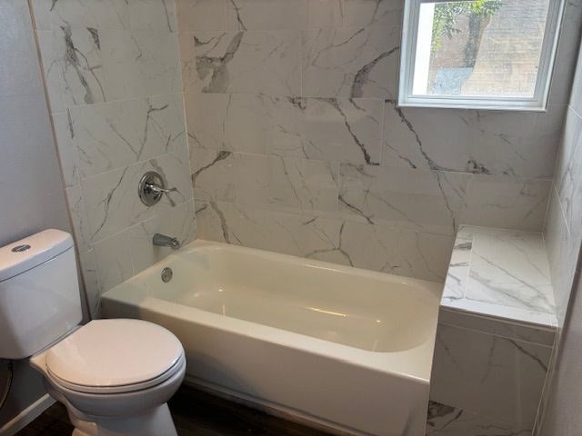 bathroom featuring tiled shower / bath and toilet