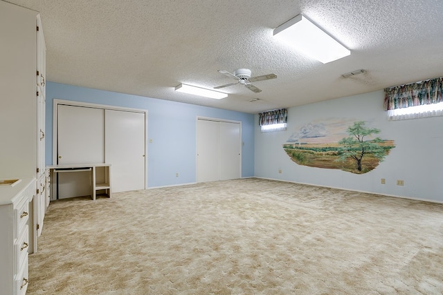 spare room featuring light carpet, a textured ceiling, and ceiling fan