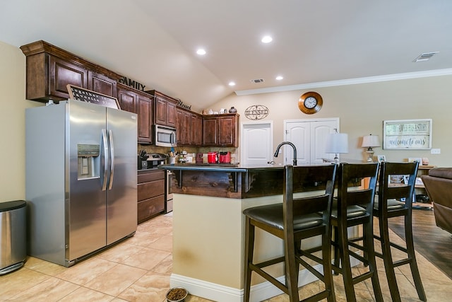 kitchen with dark brown cabinets, visible vents, appliances with stainless steel finishes, crown molding, and a breakfast bar area