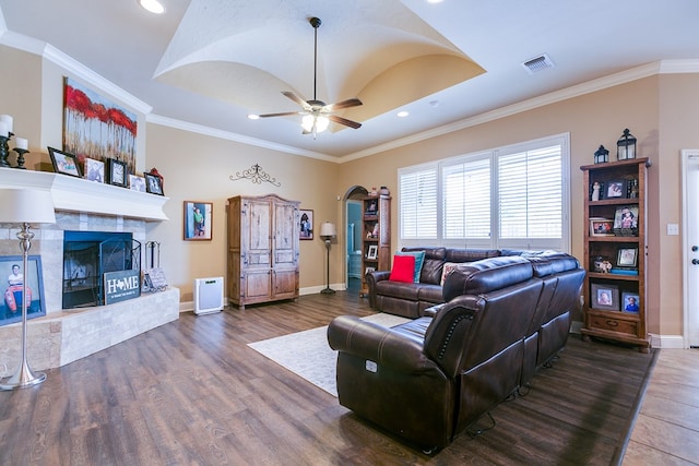 living area with wood finished floors, visible vents, arched walkways, and a fireplace
