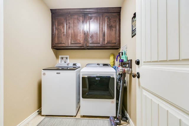 laundry area with washing machine and dryer, baseboards, and cabinet space