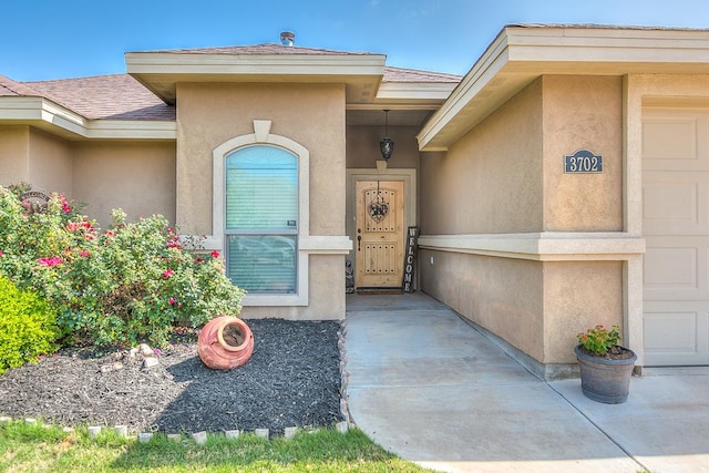 entrance to property with stucco siding and roof with shingles