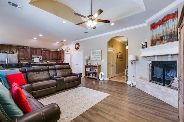 living area with dark wood finished floors, lofted ceiling, visible vents, a ceiling fan, and arched walkways