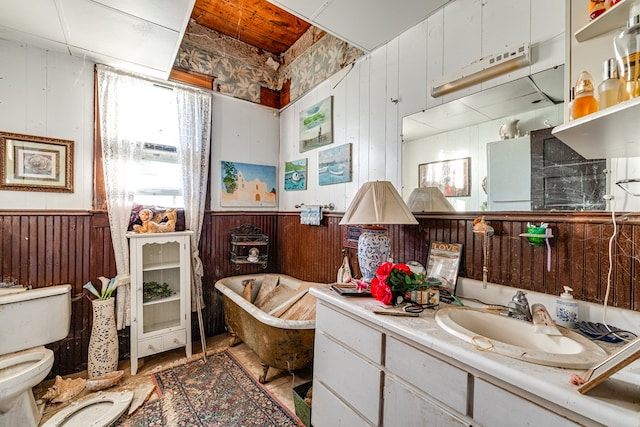 219 Bird St, San Angelo, TX 79603 - bathroom featuring vanity, wooden walls, toilet, and a freestanding bath