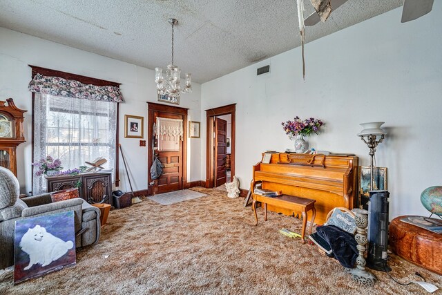 219 Bird St, San Angelo, TX 79603 - living area featuring carpet, baseboards, visible vents, a textured ceiling, and a notable chandelier