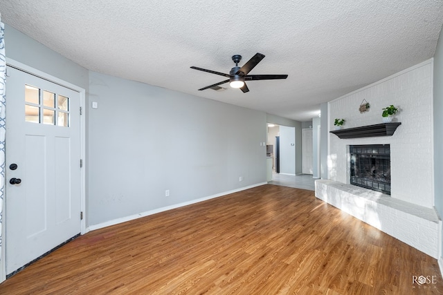 unfurnished living room featuring wood-type flooring, ceiling fan, a fireplace, and a textured ceiling