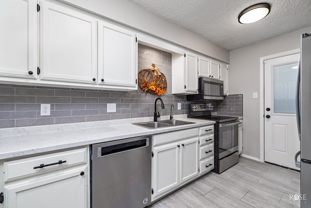 kitchen with stainless steel appliances, sink, a textured ceiling, and white cabinets