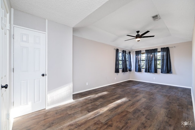 spare room with dark hardwood / wood-style flooring, ceiling fan, a tray ceiling, and a textured ceiling