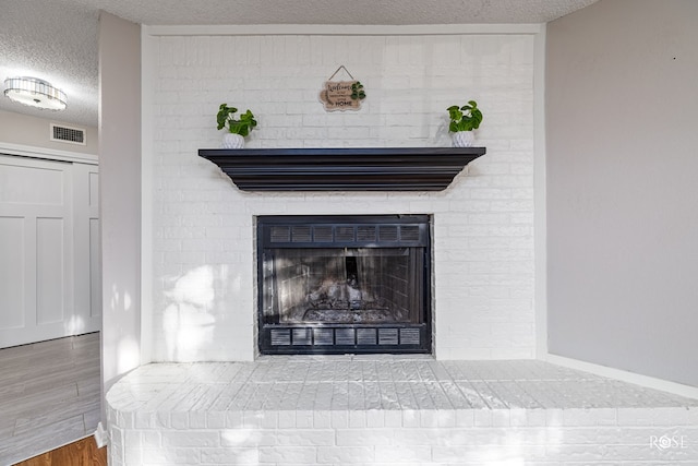 interior details featuring hardwood / wood-style floors, a brick fireplace, and a textured ceiling