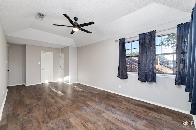 empty room featuring ceiling fan, dark hardwood / wood-style floors, vaulted ceiling, and a textured ceiling