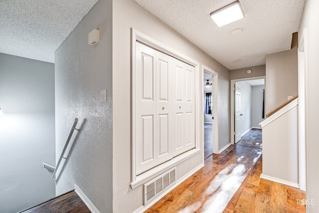 corridor featuring a textured ceiling and light wood-type flooring