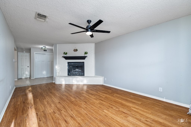 unfurnished living room with wood-type flooring, a fireplace, a textured ceiling, and ceiling fan