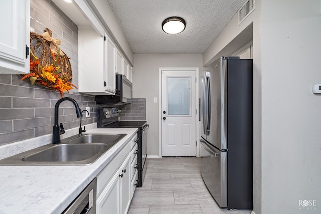 kitchen featuring tasteful backsplash, sink, white cabinets, stainless steel fridge, and electric range