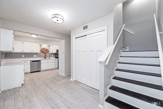 kitchen with white cabinetry, sink, backsplash, stainless steel appliances, and a textured ceiling