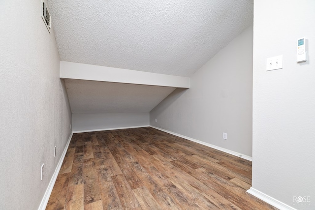 bonus room featuring lofted ceiling, dark hardwood / wood-style floors, and a textured ceiling