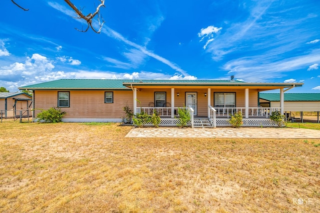 view of front of home featuring metal roof, covered porch, and a front yard