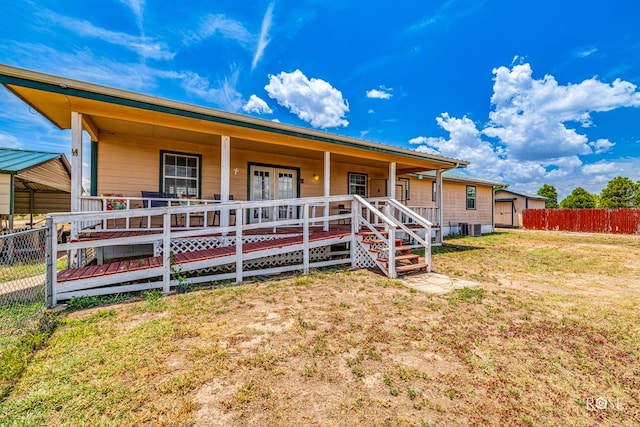 view of front facade with central AC unit, fence, a porch, a front lawn, and french doors