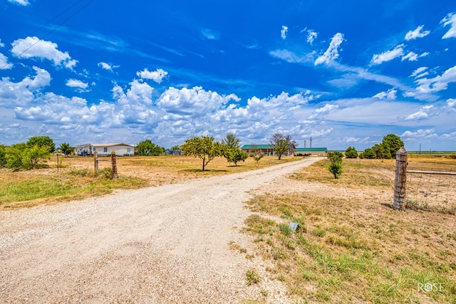 view of road featuring gravel driveway and a rural view
