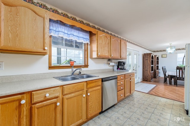 kitchen featuring a wealth of natural light, dishwasher, light countertops, and a sink