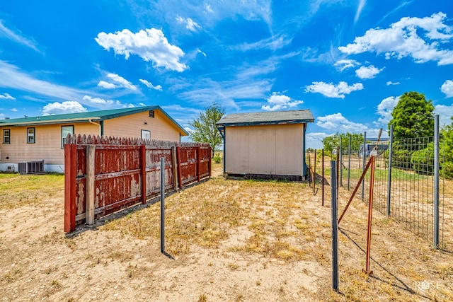 view of yard featuring fence, an outbuilding, central AC unit, and a shed