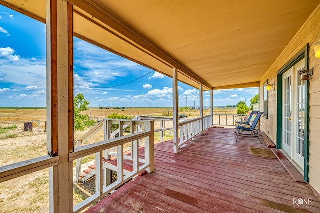 deck with a rural view and fence