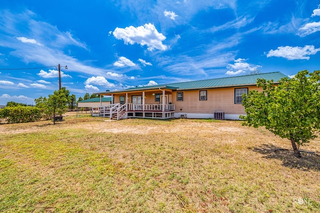 back of property with a yard, metal roof, cooling unit, and a porch