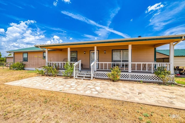 ranch-style home featuring covered porch and a front lawn