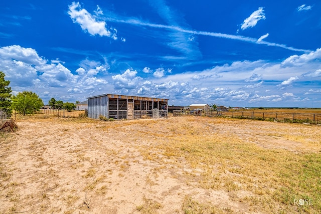 view of yard featuring an outbuilding, a rural view, and an exterior structure