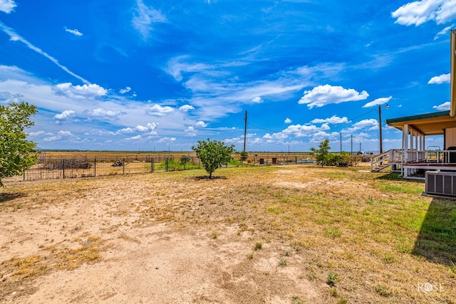 view of yard featuring a rural view, central air condition unit, and fence