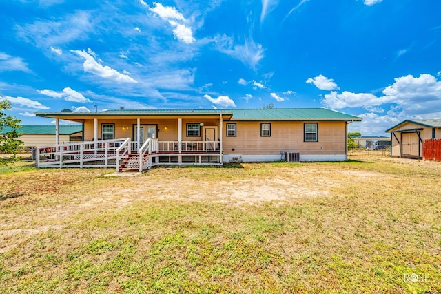 rear view of house with a porch, a yard, fence, and metal roof