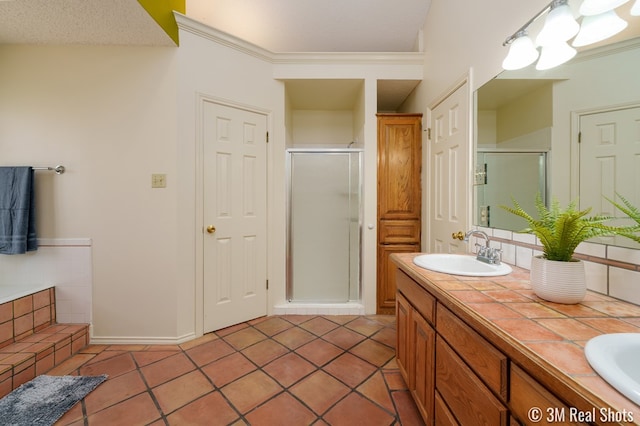 bathroom with double vanity, a stall shower, a sink, tile patterned flooring, and crown molding