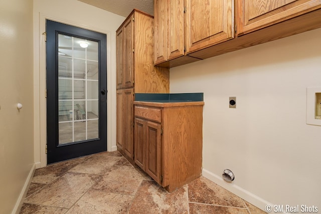 laundry room with stone finish flooring, baseboards, hookup for a washing machine, cabinet space, and hookup for an electric dryer