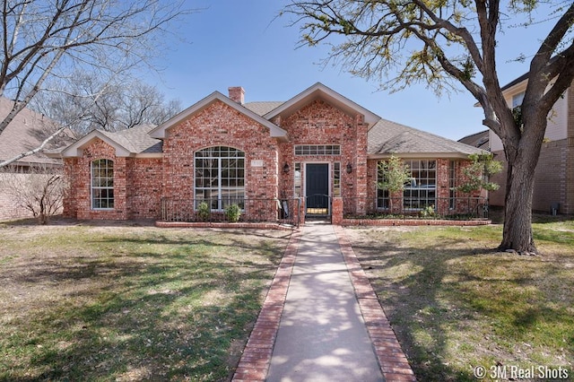 ranch-style house featuring a front yard, brick siding, roof with shingles, and a chimney