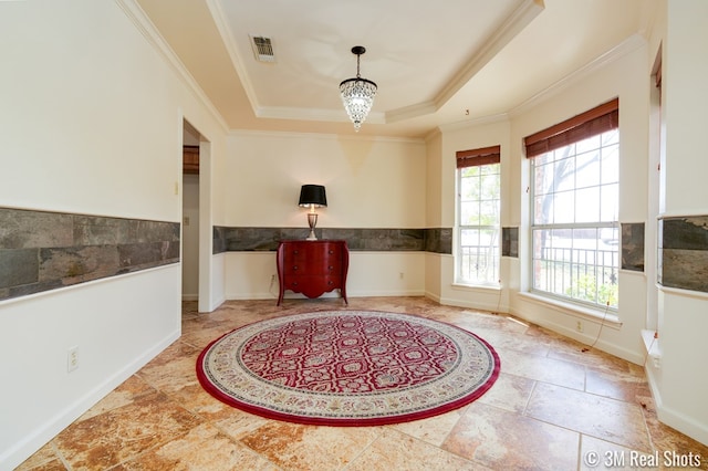 interior space with a wainscoted wall, visible vents, crown molding, a raised ceiling, and a chandelier