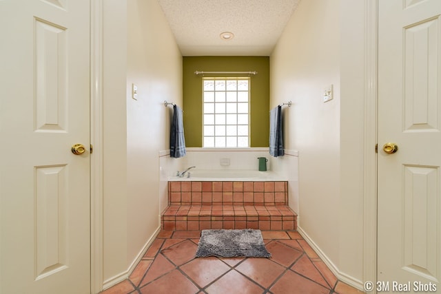 bathroom featuring a garden tub, baseboards, a textured ceiling, and tile patterned flooring