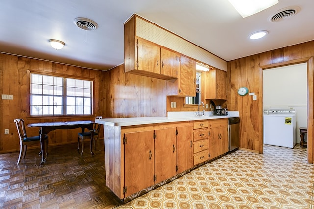 kitchen featuring visible vents, wooden walls, washer / clothes dryer, and dishwasher