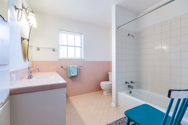 bathroom with wainscoting, toilet, tile patterned floors, bathtub / shower combination, and tile walls