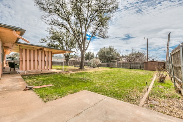 view of yard featuring an outbuilding, a patio, a storage unit, and a fenced backyard