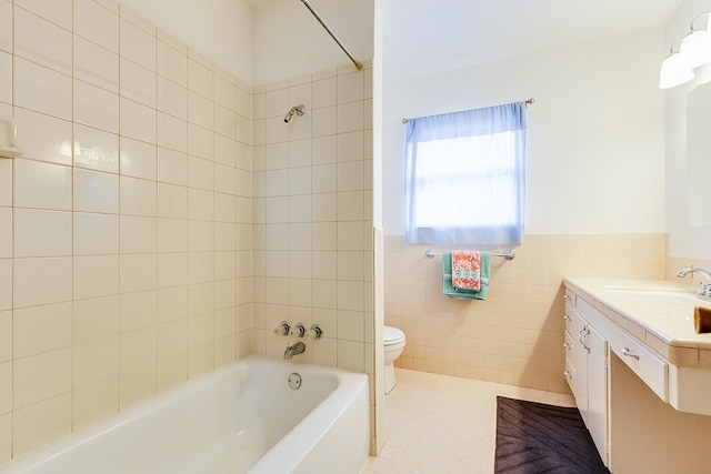 bathroom featuring toilet, tile patterned floors, bathtub / shower combination, vanity, and tile walls