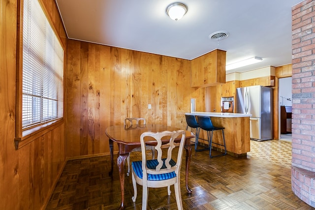 dining room with wooden walls and visible vents