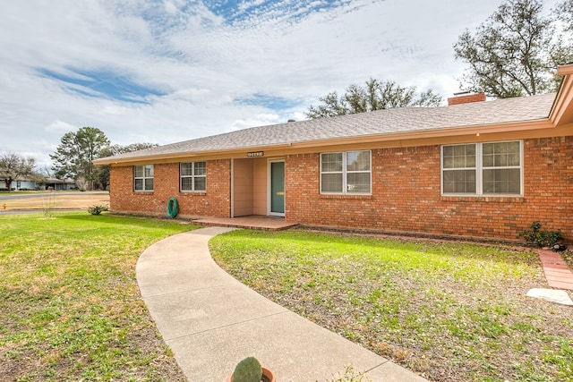 ranch-style house with brick siding, a chimney, and a front yard