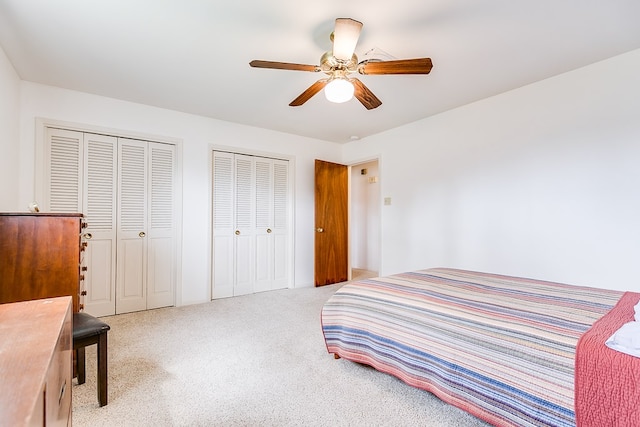 bedroom featuring carpet, two closets, and a ceiling fan