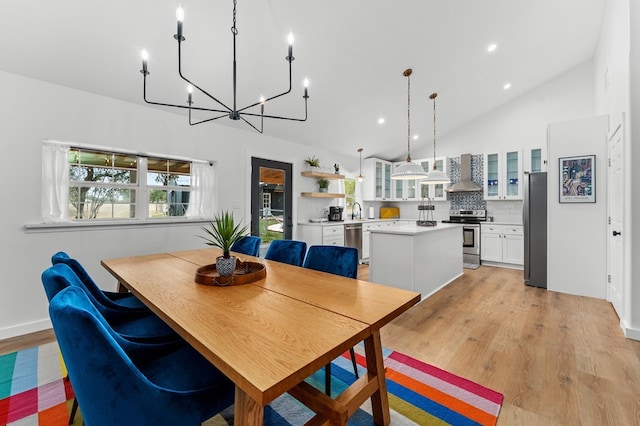 dining room featuring sink, high vaulted ceiling, and light hardwood / wood-style flooring
