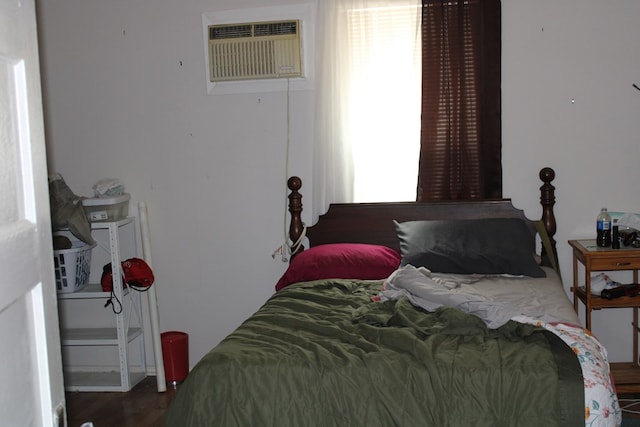 bedroom featuring dark hardwood / wood-style flooring and an AC wall unit