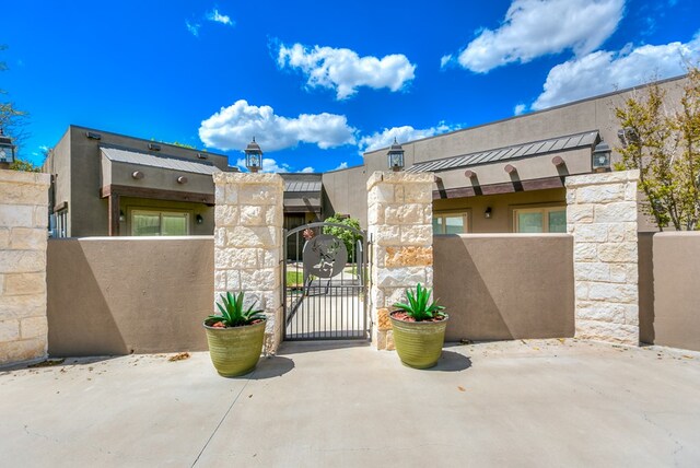 exterior space with fence, a gate, and stucco siding