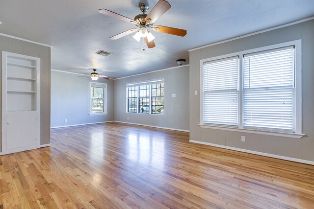 unfurnished room with crown molding, a textured ceiling, built in features, and light wood-type flooring