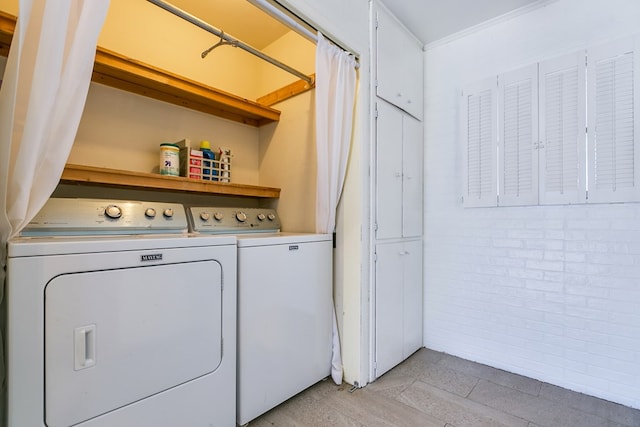 washroom with brick wall and washing machine and clothes dryer