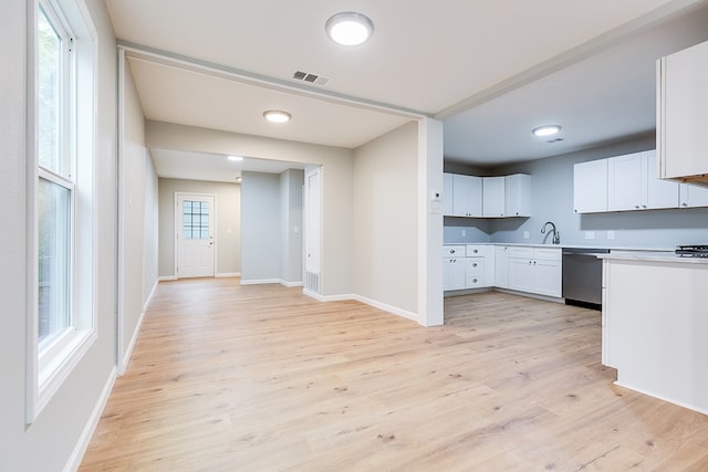 kitchen with sink, white cabinetry, light hardwood / wood-style flooring, dishwasher, and a healthy amount of sunlight