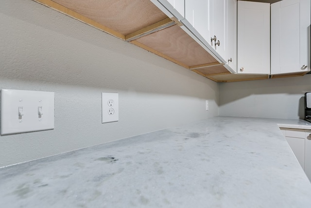 interior space with concrete floors and white cabinets